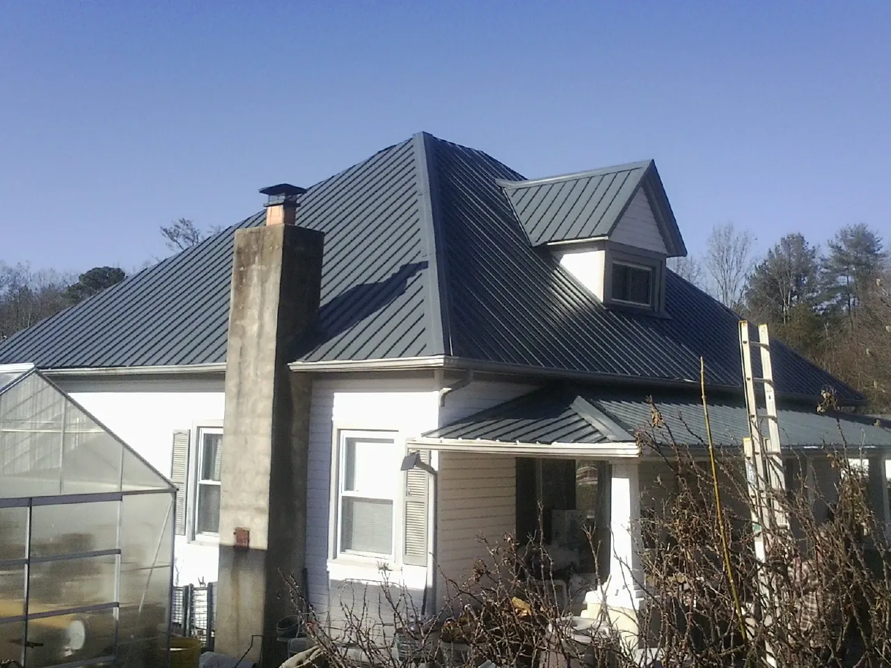 Dark blue standing seam metal roof on a white farmhouse with dormer — Slate & Tile Roof Repair by Roofing Brothers in Aroma Park