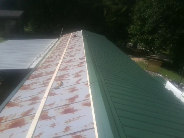 Old rusted panels beside newly installed green metal roofing — Wind Damage Roof Repair by Roofing Brothers in Aroma Park