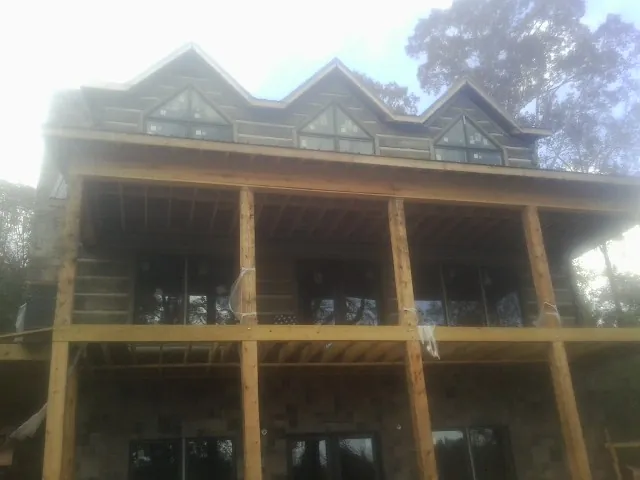 Dormers and porch framing on a large log home under construction — Roof Coating work by our crew in Aroma Park