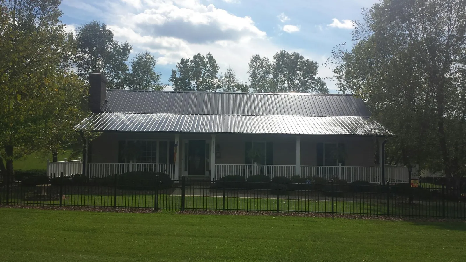 Gray metal roof on a brick ranch with a full width front porch — Gutter Guard Installation work by our crew in Aroma Park