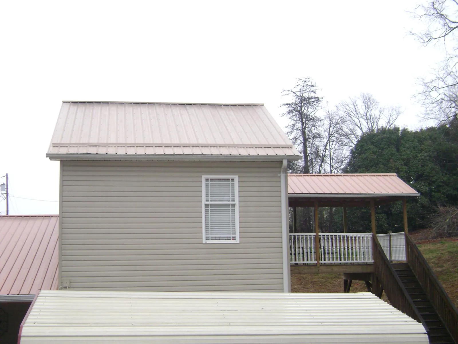 Tan metal roofs on a two story addition and attached porch, from a Roof Replacement job in Aroma Park