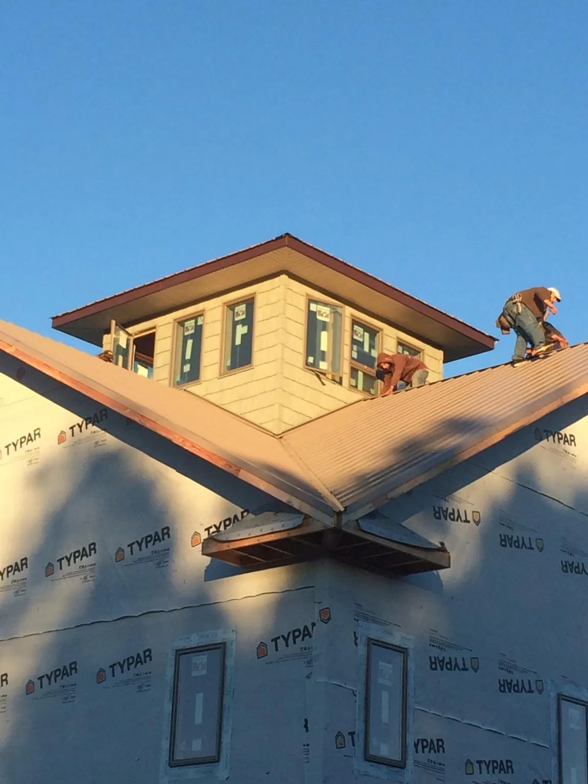 Roofers working around a rooftop cupola on a new metal roof at sunset — Roof Waterproofing in Aroma Park by Roofing Brothers